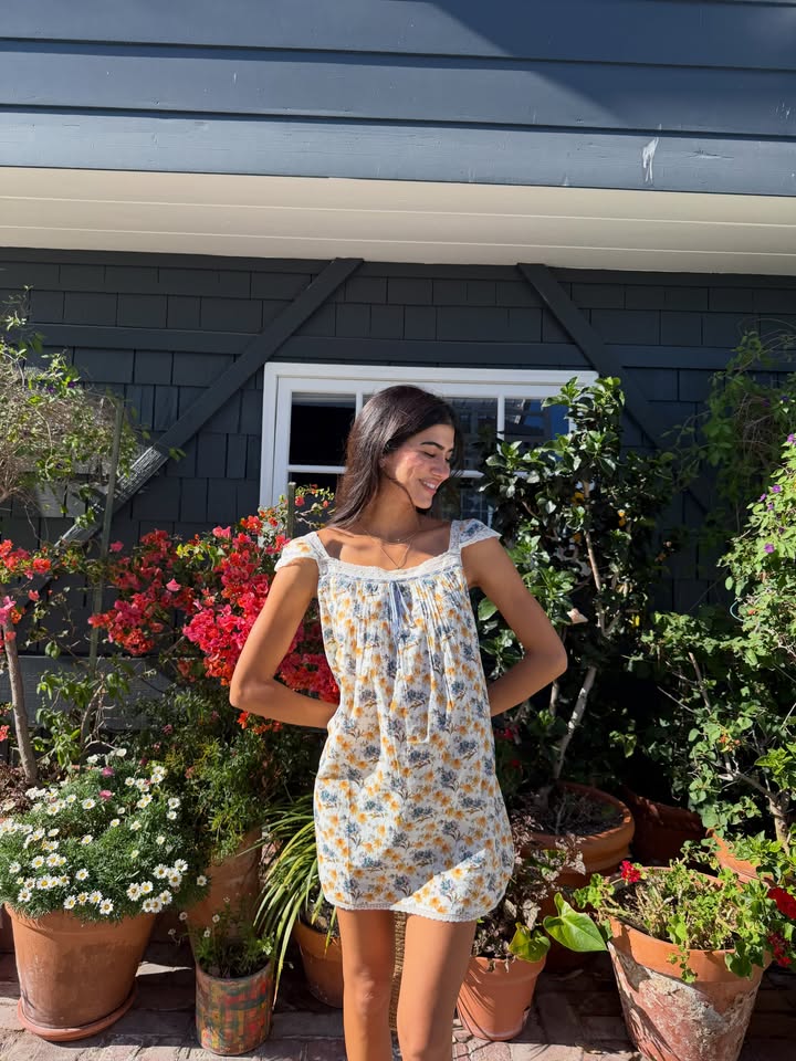 Sanaz Fakhimi, founder of SAFA Agency, standing among flowers in the sunshine